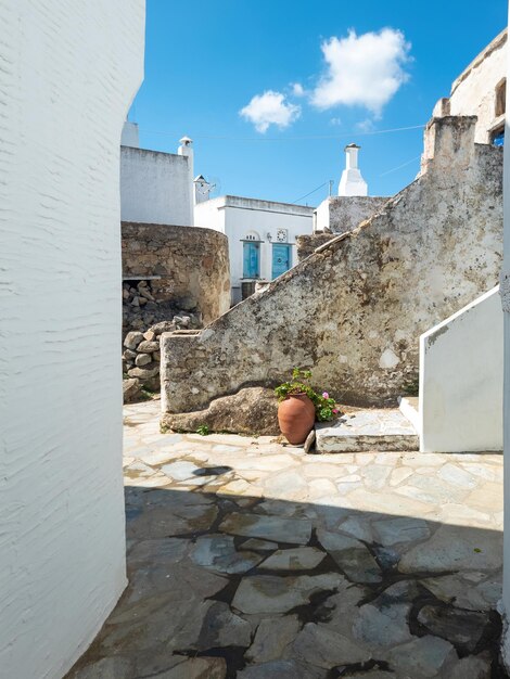 Grécia Cíclades Ilha de Tinos Aldeia de Volax Velhos muros de pedra entre edifícios caiados de branco Vertical