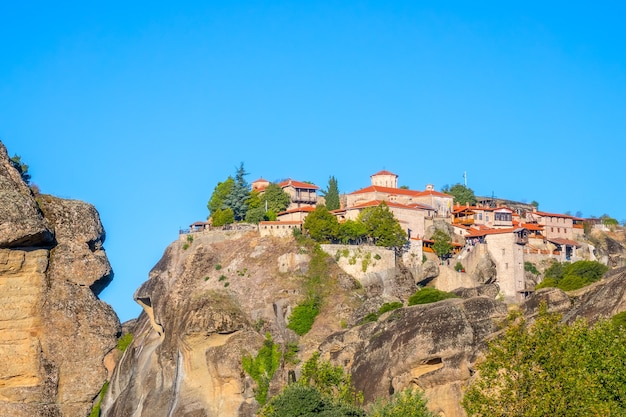 Grecia. Un claro día de verano en Meteora. Varios edificios de un monasterio de roca con techos rojos contra un cielo azul sin nubes