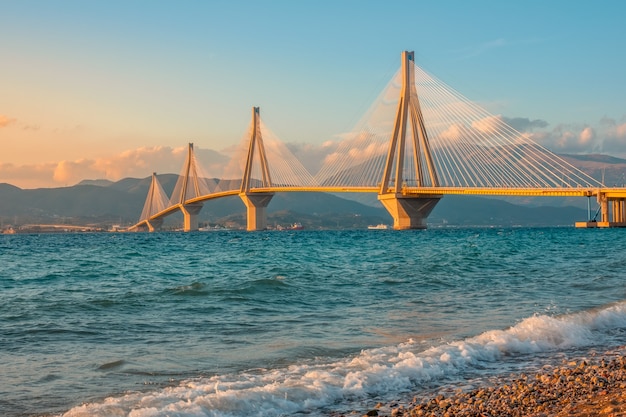 Grecia. Golfo de Corinto y puente Río Antirio. Iluminación del atardecer en una playa de guijarros