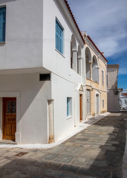 Grécia Ilha de Andros Cidade de Chora Cíclades Beco de paralelepípedos casas antigas sol céu azul Vertical