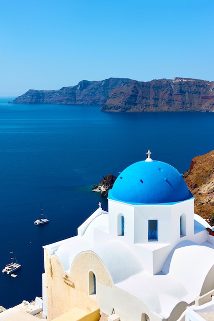 Grécia, Ilha de Santorini. Vista panorâmica com igreja branca na costa alta junto ao mar. Paisagem grega