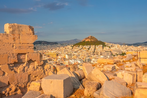 Grécia. pôr do sol em atenas. ruínas de mármore em primeiro plano. vista de um ponto alto nos telhados da cidade e no monte lycabettus