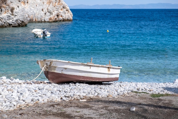 Foto grécia praia de seixos barco ancorado mar calmo mani lacônia peloponeso águas cristalinas