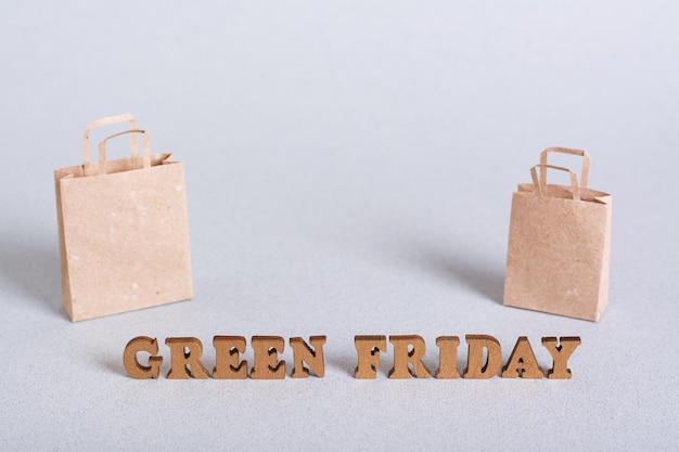 Green Friday-Konzeptschriftzug und Papiertüten auf grünem Hintergrund