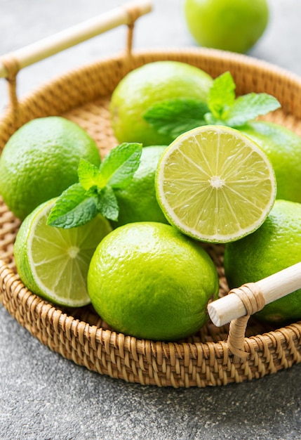 Green Limes com folhas de hortelã fresca na bandeja de vime