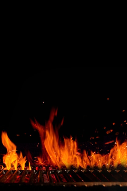 Grelha de churrasco de churrasco quente vazia com faíscas de fogo ardente e carvão em brasa em fundo preto ...