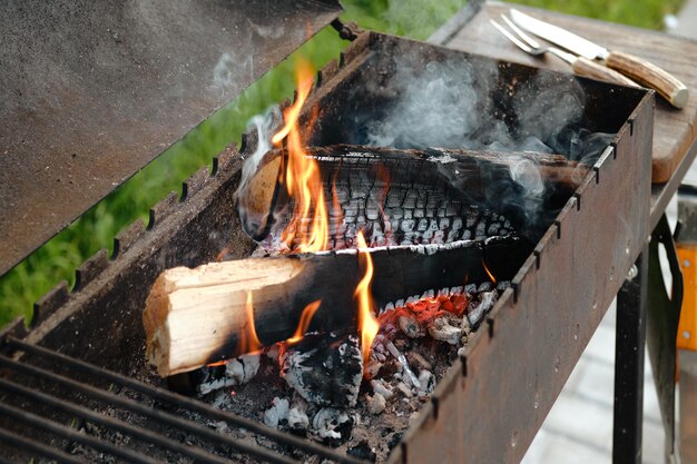 Grelha de metal com tronco ardente e garfo e faca para bife