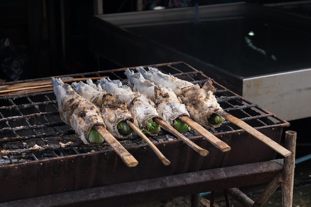 Grelha de peixe Snakehead grelhado com crosta de sal no fogão a carvão no mercado