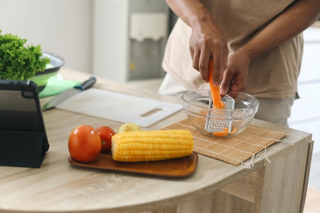 Grelhando à mão cenouras frescas maduras na mesa da cozinha Conceito de comida saudável