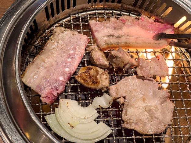 Grelhar carne de barriga de porco em uma rede de churrasco redonda no restaurante para comer