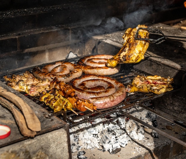 Foto grelhar detalhes de comida de um churrasco com espetos de salsicha e frango em um dia ensolarado