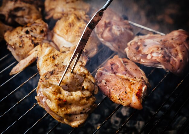 Grelhar frango temperado na grade na churrasqueira a carvão. Shalow DOF.