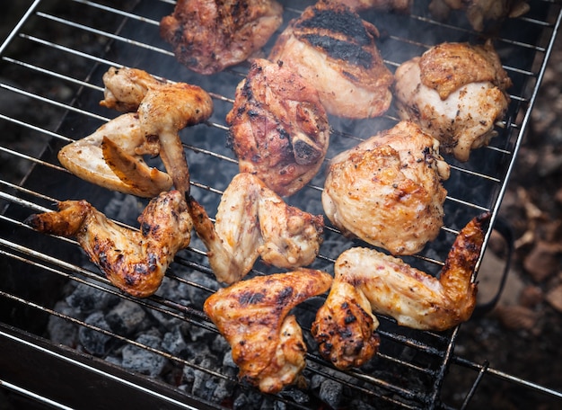 Grelhar frango temperado na grade na churrasqueira a carvão. Shalow DOF.