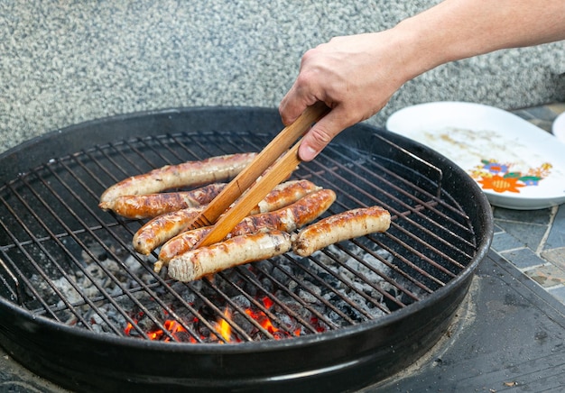 grelhe o bife de salsichas na grelha em fogo aberto