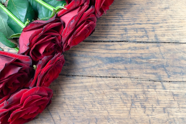 Grenze der roten rosen am hölzernen hintergrund des schmutzes