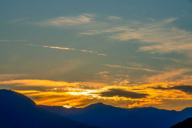 Griechenland. Sonnenuntergang über den Silhouetten der Berge. Goldene Wolken am dunkelblauen Himmel