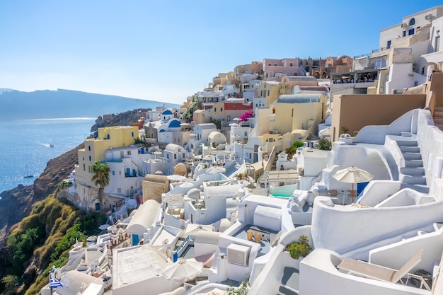 Griechenland. Sonniger Sommertag auf Santorini. Oia Gebäude und Terrassen mit Blumen auf der Caldera mit Meerblick