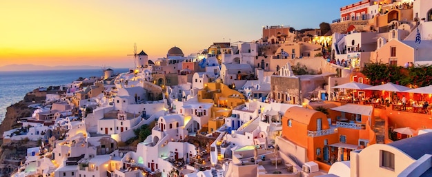 Griechenland Urlaub Hintergrund Berühmtes ikonisches Dorf Oia mit traditionellen weißen Häusern und Windmühlen während des farbenfrohen Sonnenuntergangs Insel Santorini Griechenland