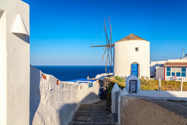 Griechenland Urlaub ikonischer Hintergrund Berühmte Windmühle im Dorf Oia mit traditionellen weißen Häusern während des sonnigen Sommertages Insel Santorini Griechenland