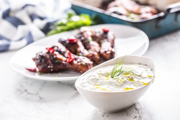 Griechische Dip-Sauce oder Dressing Tzatziki mit Hähnchenkeulen.