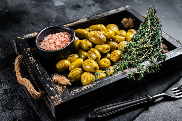 Griechische gegrillte Oliven mit Knoblauch-Olivenöl und Gewürzen in Holzschale Schwarzer Hintergrund Draufsicht