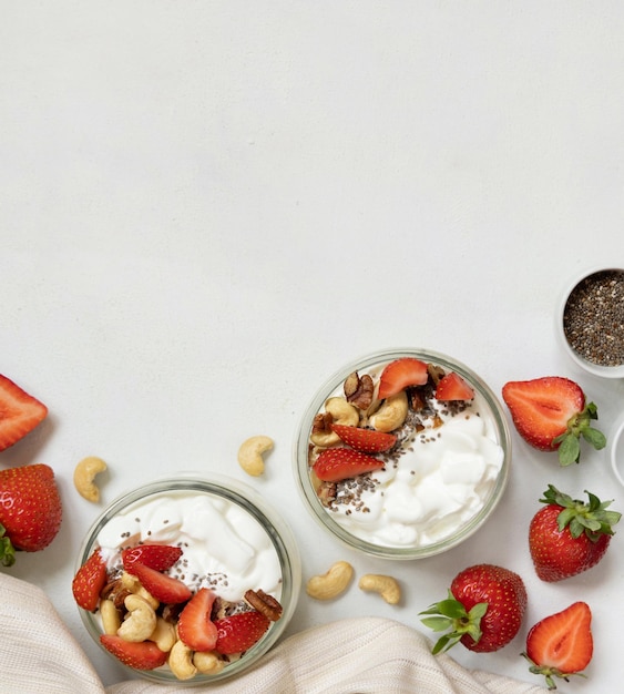 Griechische Joghurtnüsse und Erdbeeren in Gläsern auf einem weißen Tisch mit Kopierraum