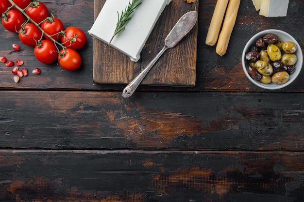 Griechische Salatzutaten eingestellt, auf dunklem hölzernem Hintergrund, flach liegen mit Kopienraum für Text