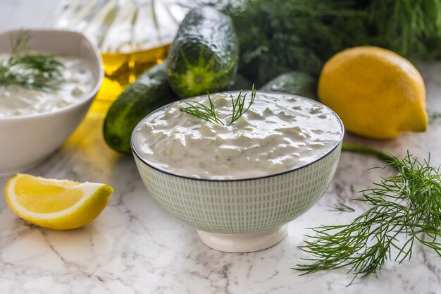 Griechischer Dip oder Dressing Tzatziki zubereitet mit Gurken-Sauerrahm-Joghurt-Olivenöl und frischem Dill