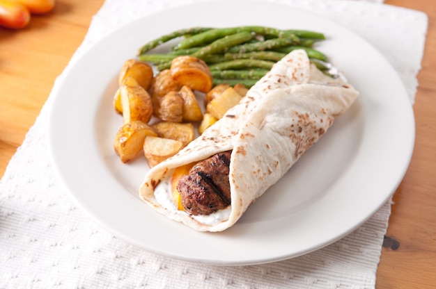 Griechischer Hamburger gerollt in einem Fladenbrot mit Fingerling Pota