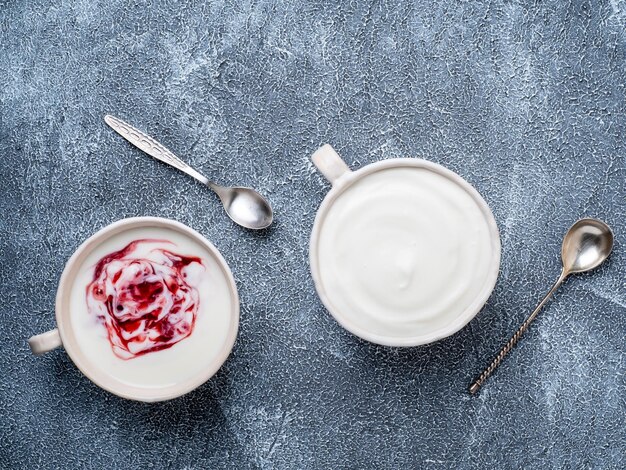 Foto griechischer joghurt mit marmelade in einer weißen schüssel auf einem grauen blauen beton-stein-tisch