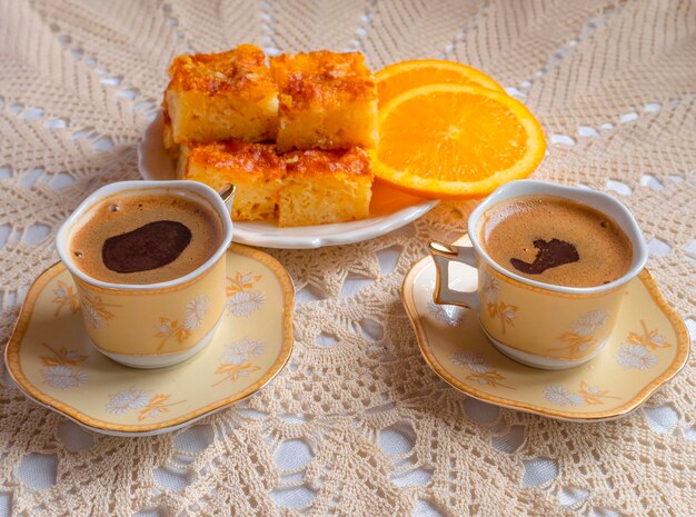 Griechischer Orangenkuchen mit Orangenscheiben und Kaffee auf einer handgefertigten gestrickten Tischdecke in Griechenland