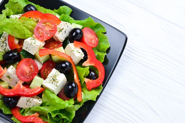 Griechischer Salat auf einem weißen hölzernen Hintergrund