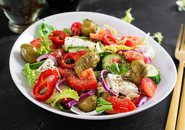 Foto griechischer salat aus frischen tomaten, paprika, gurken, roten zwiebeln, feta-käse und grünen oliven. gesundes vegetarisches essen.