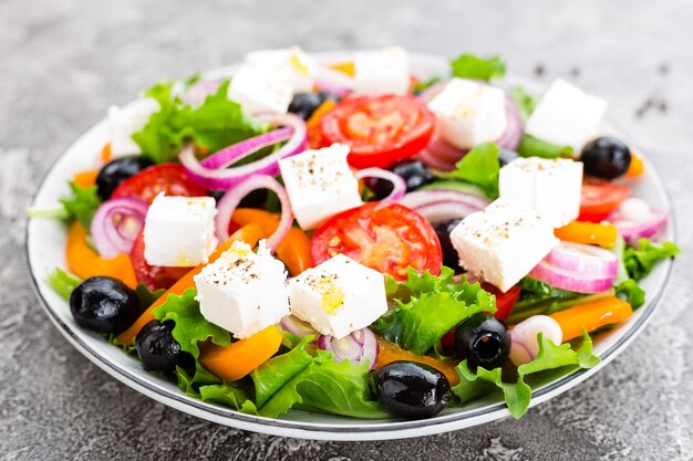 Griechischer Salat Frischer Gemüsesalat mit Tomaten, Zwiebeln, Gurken, Paprika, Oliven, Salat und Feta-Käse. Griechischer Salat auf dem Teller