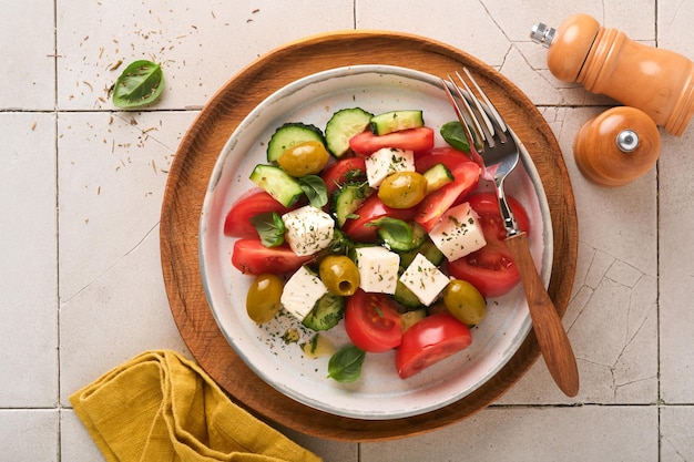 Griechischer Salat Frischer griechischer Salat mit frischem Gemüse, Tomaten, Gurken, grünen Oliven und Feta-Käse auf altem grauem Betontischhintergrund Draufsicht