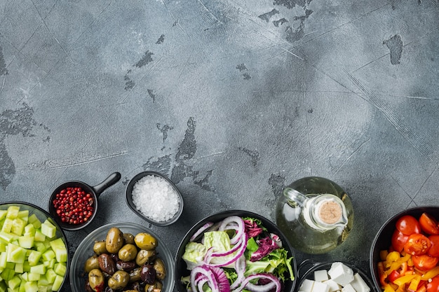 Griechischer Salat Hauptzutaten frische Oliven mischen, Feta-Käse, Tomaten, Pfeffer, auf grauem Tisch, Draufsicht flach legen