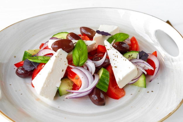 Griechischer Salat im Teller auf weißem Holzhintergrund