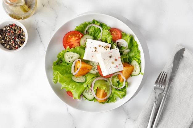 Griechischer Salat in weißer Schüssel im sonnigen Sommerlicht Frischer Gemüsesalat Draufsicht