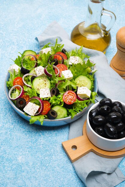 Griechischer Salat mit Tomaten, Gurken, Oliven und Feta-Käse in einem Teller auf Betonhintergrund, typisch griechische Küche