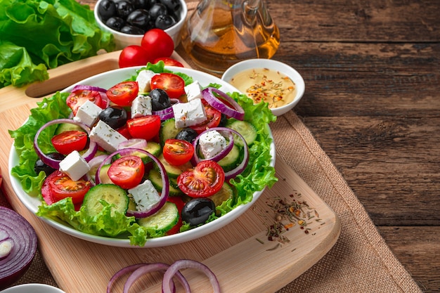 Griechischer Salat, Oliven und Butter auf Holz