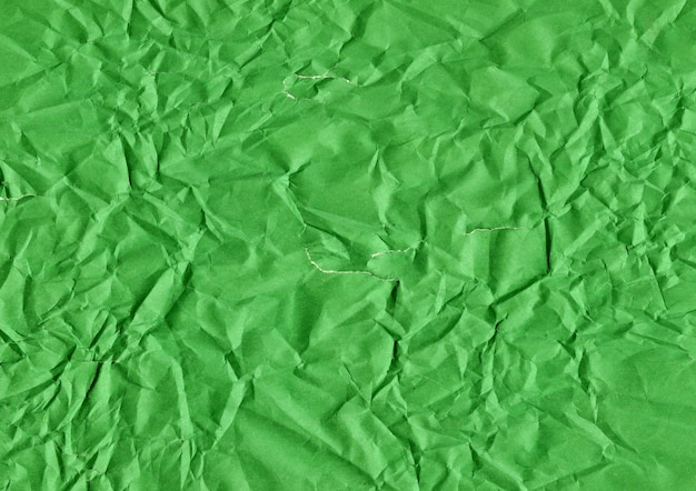 Grietas y lágrimas en una hoja de papel arrugada verde