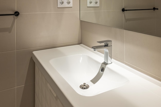 Grifo de agua completamente nuevo en baño de lujo con azulejos beige interior moderno en detalle