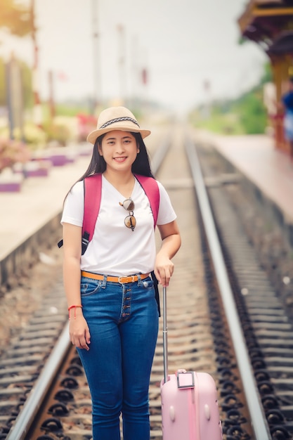 Gril asiático joven que camina en la estación de tren antes del viaje