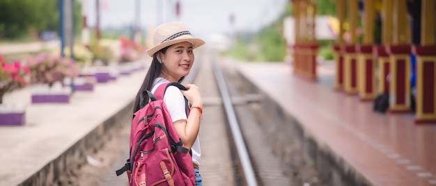 Gril asiático joven que camina en la estación de tren antes de viaje.