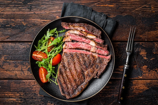 Grill gegrilltes und in Scheiben geschnittenes Wagyu Rib Eye Beefsteak auf einem Teller Dunkler Hintergrund Ansicht von oben