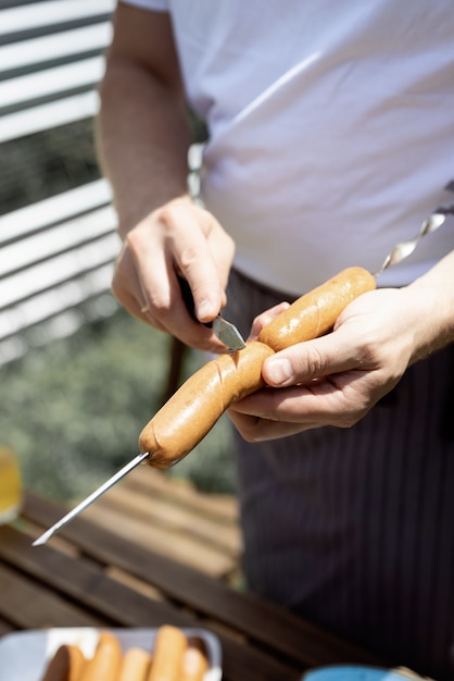 Grill im Hinterhof. Mans Hände grillen Kebab und Gemüse auf Metallspießen.