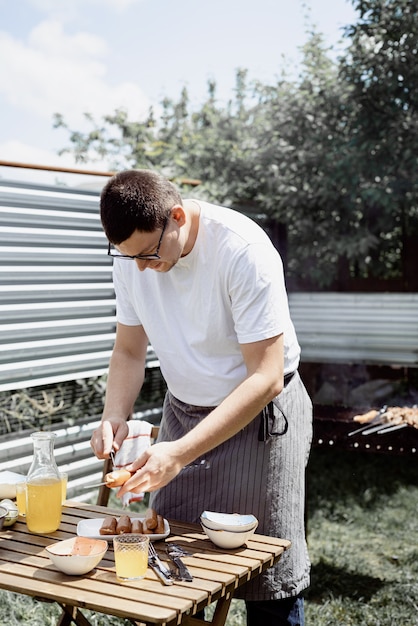 Grill im Hinterhof. Mans Hände grillen Kebab und Gemüse auf Metallspießen.