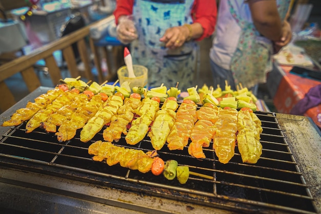 Grillando carne y verduras en un puesto de mercado en Tailandia