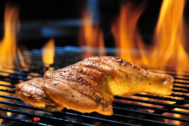 Grillbrathähnchenschenkel auf dem brennenden Grill grillen