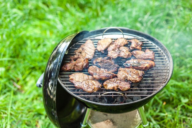 Grillen von Schweinefleisch mit Grillzeug. Horizontale Nahaufnahme mit selektivem Fokus